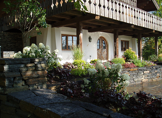 Picture of chalet style home with large flowering bushes and gardens