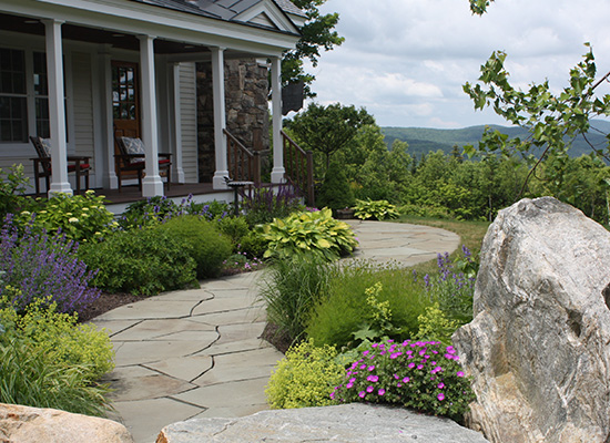 Picture of a house in the mountains with stone pathways leading to a low porch