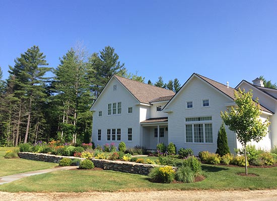 Picutre of large white home with stone wall and landscaping